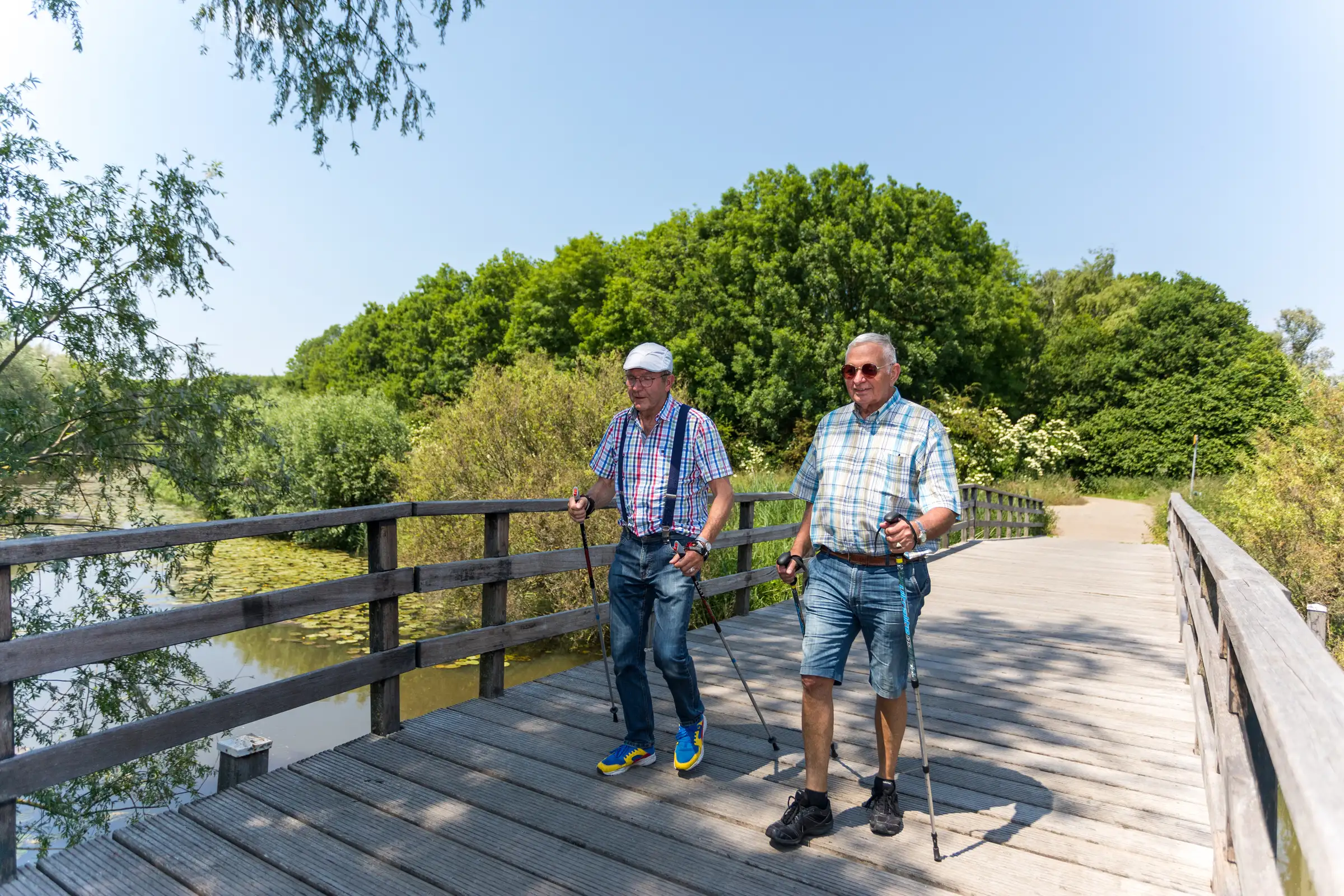 Twee oudere heren die samen aan Nordic walking doen.